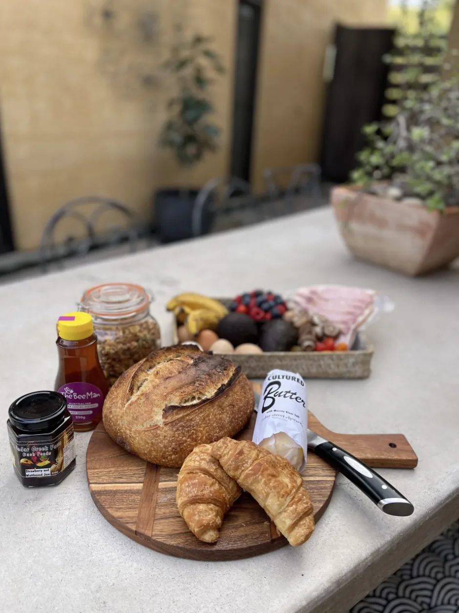 Breakfast basket — sourdough, croissants, honey, jam, eggs and bacon