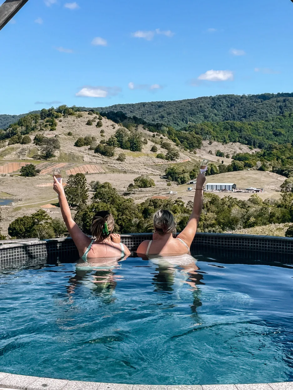 Two guests in the pool overlooking the hills